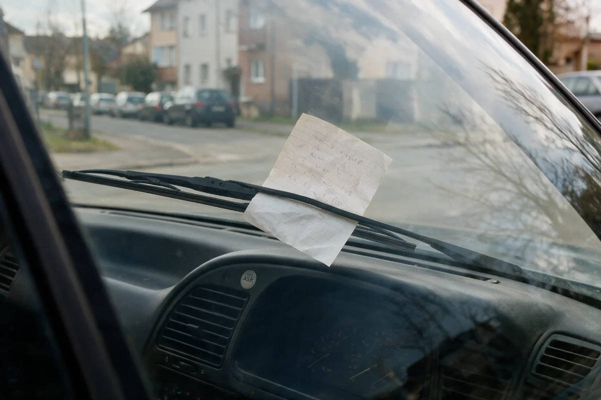 Handwritten note with contact details left under a car windscreen wiper